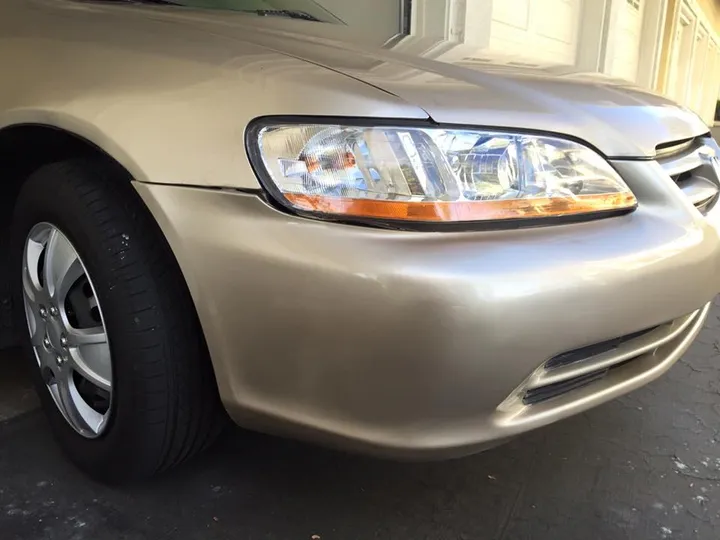 A recently refinished headlight on a tan car