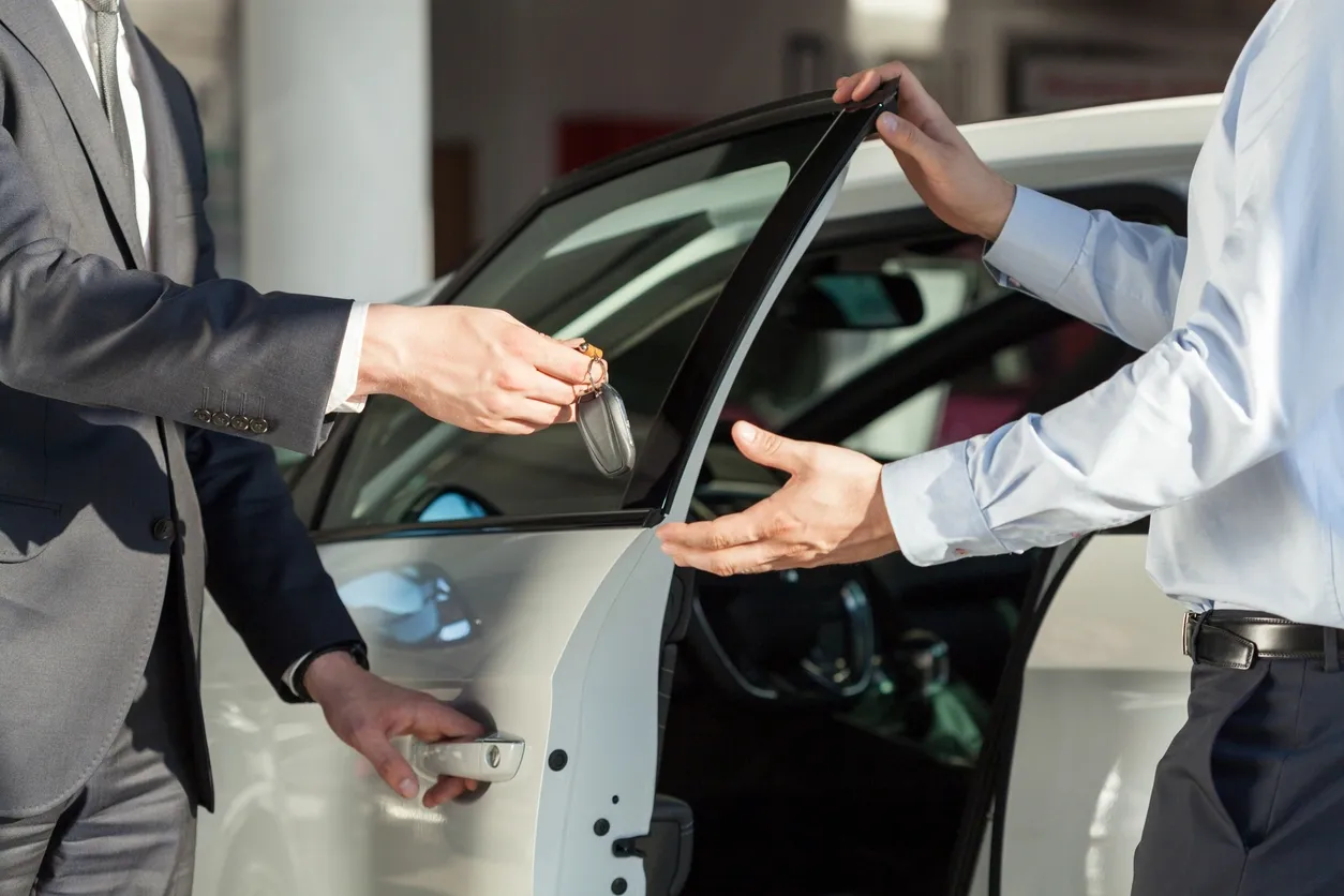 A car salesperson handing a new owner keys to a vehicle
